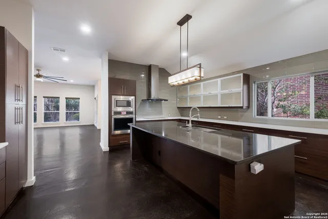 a large kitchen with stainless steel appliances a large counter top a sink a center island and stainless steel appliances