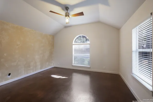 an empty room with wooden floor fan and windows