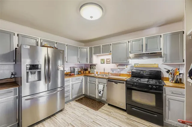 a kitchen with granite countertop a refrigerator stove and sink