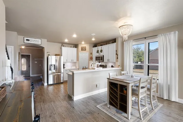 a kitchen with stainless steel appliances kitchen island granite countertop a table chairs cabinets and wooden floor
