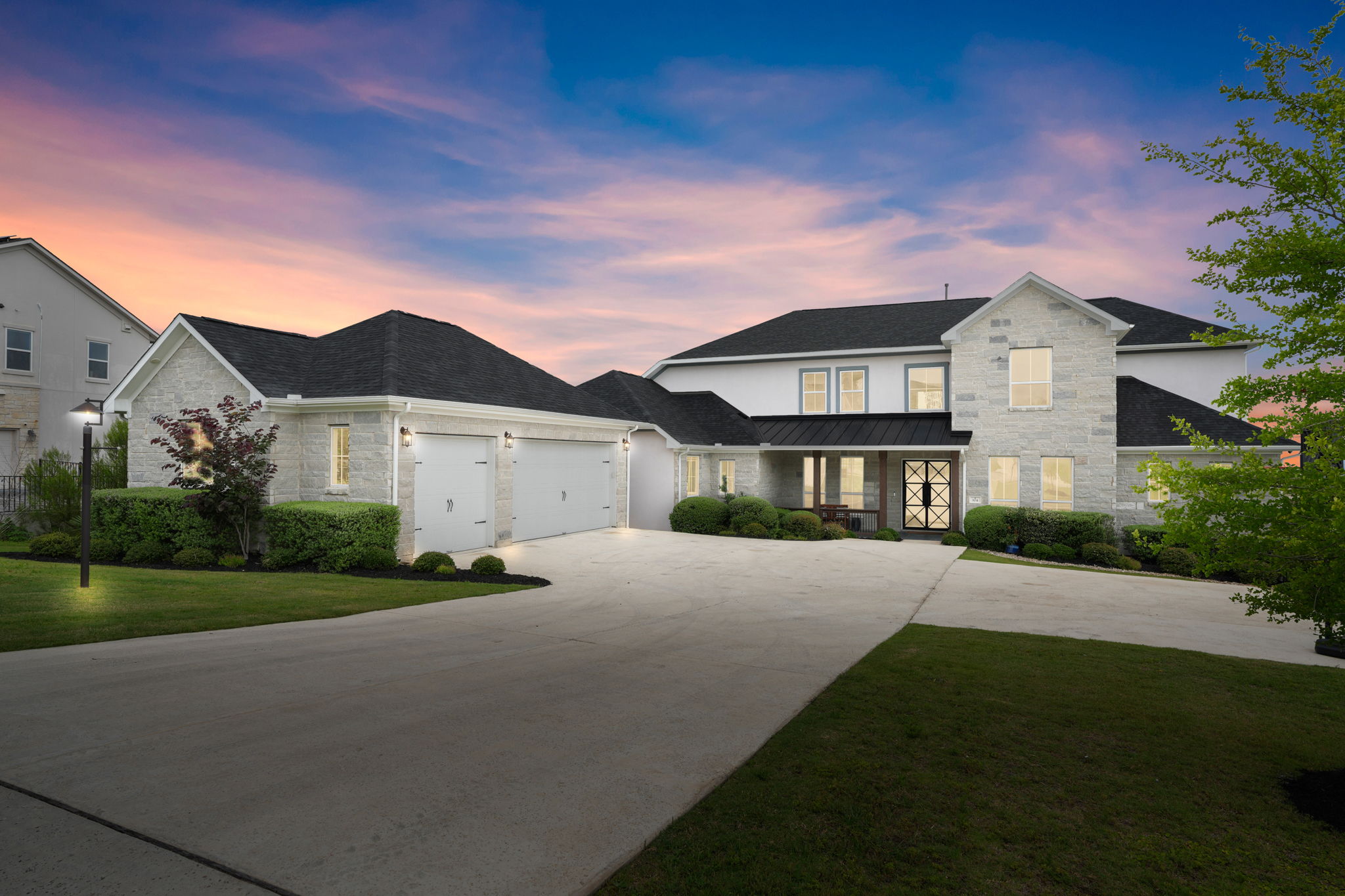 104 Lodestone Cove Austin, TX 78738 - Photo 2 of 40 An inviting drive leads to this contemporary stone residence, framed by a vibrant sunset.