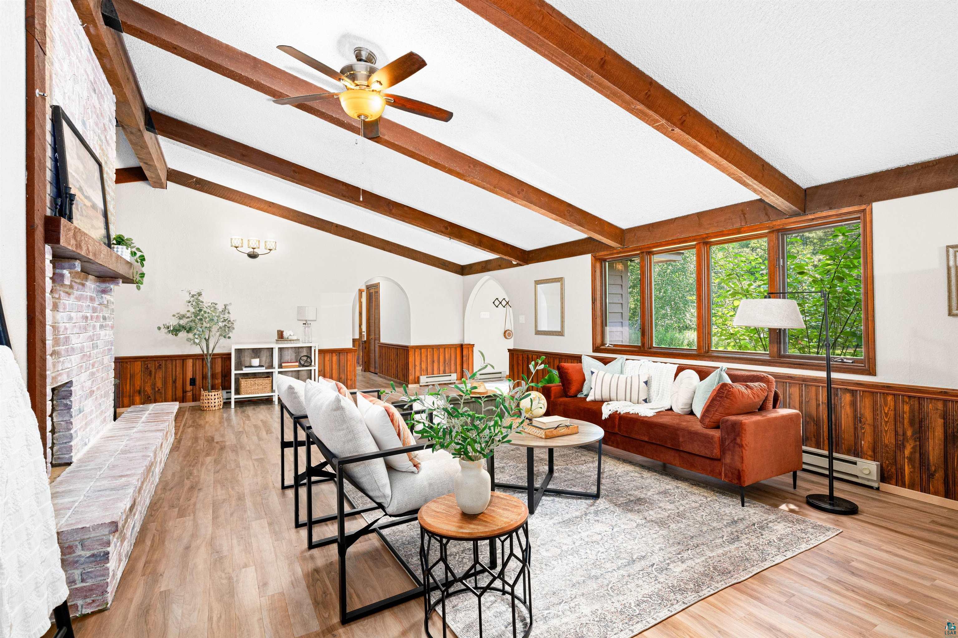 3837 Kansy Road Superior, WI 54880 - Photo 5 of 50 Living room with vaulted ceiling with beams, a baseboard heating unit, ceiling fan, light hardwood / wood-style floors, and a brick fireplace