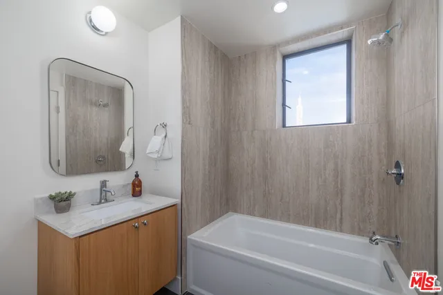 a bathroom with a bathtub sink vanity and mirror