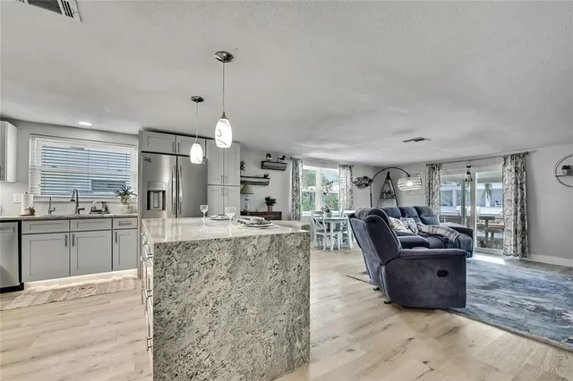 a kitchen with stainless steel appliances granite countertop a stove a refrigerator a kitchen island a sink and a refrigerator