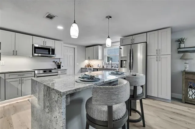 a kitchen with kitchen island a center island and stainless steel appliances