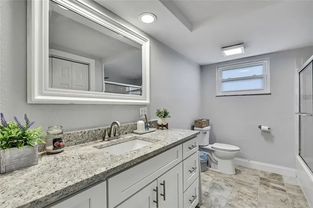 a bathroom with a granite countertop sink a toilet and a mirror