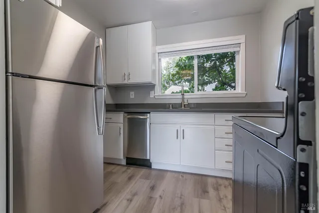 a kitchen with white cabinets and a window