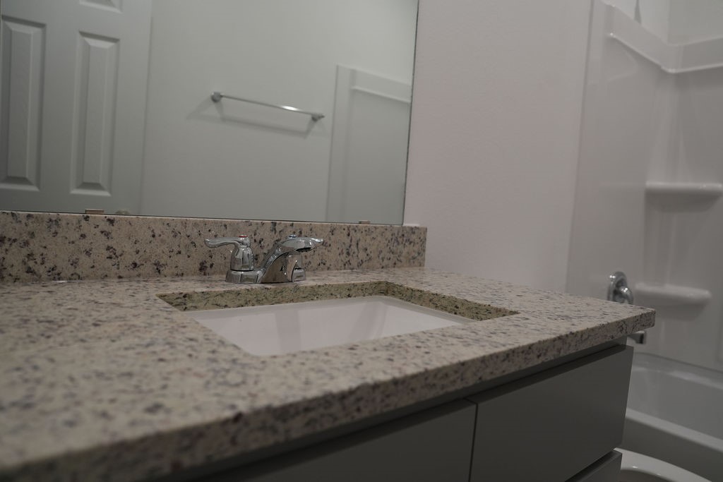 10465 Sugar Mill Drive Conroe, TX 77306 - Photo 26 of 29 a bathroom with a granite countertop sink and white cabinets