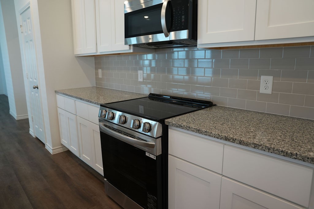 10465 Sugar Mill Drive Conroe, TX 77306 - Photo 5 of 29 a kitchen with granite countertop white cabinets and a stove