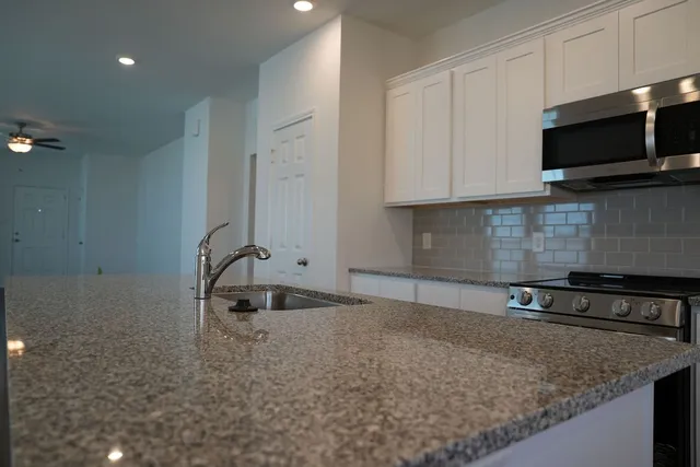 a kitchen with stainless steel appliances granite countertop a sink a stove and microwave