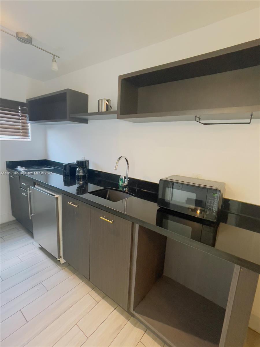 7500 Collins Avenue, Unit 114 Miami Beach, FL 33141 - Photo 4 of 9 a kitchen with stainless steel appliances granite countertop a sink and a stove