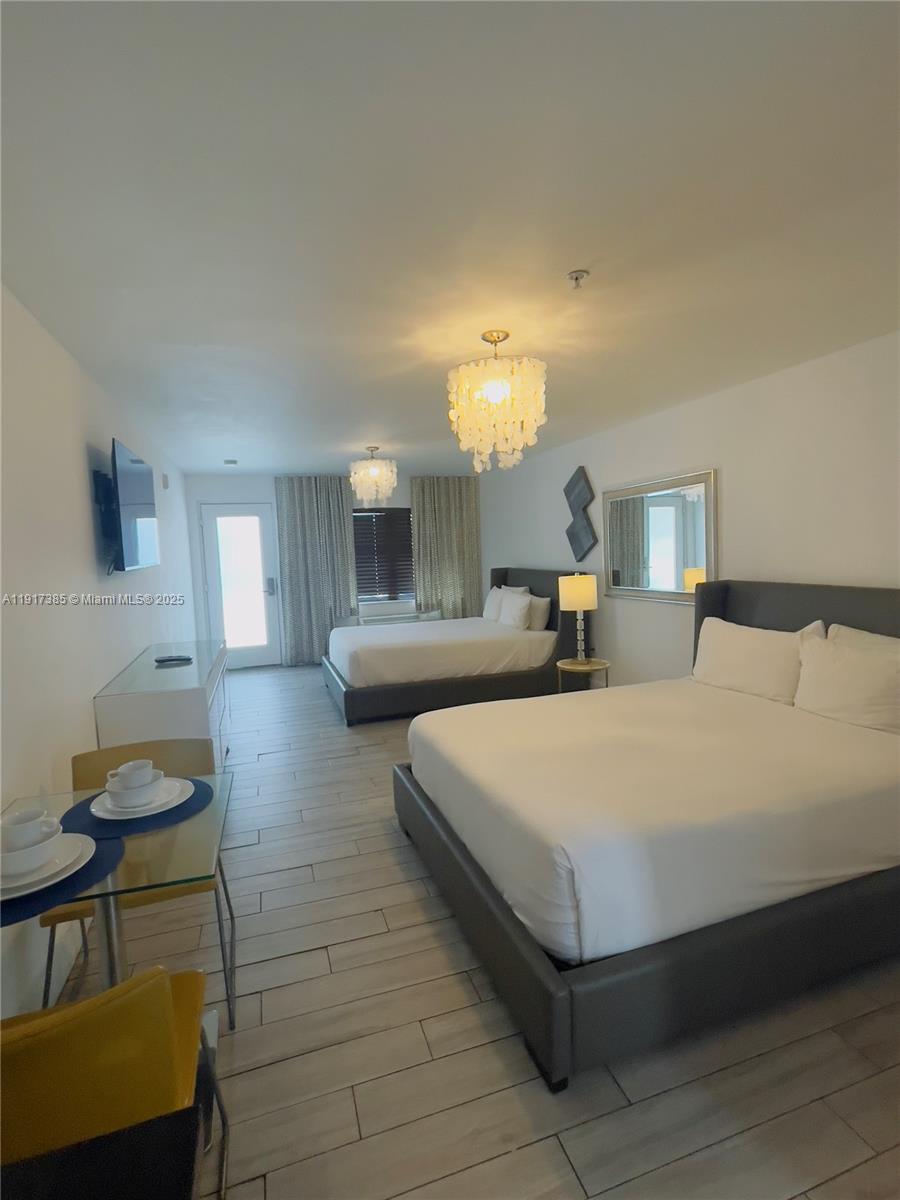 7500 Collins Avenue, Unit 114 Miami Beach, FL 33141 - Photo 5 of 9 a bedroom with a bed a mirror and lamp