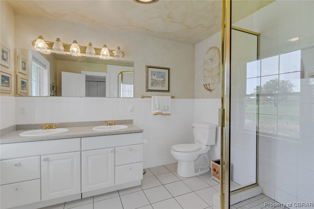 43 Locksley Court Reedville, VA 22539 - Photo 11 of 37 Bathroom with a wealth of natural light, tile walls, mirror, backsplash, light tile floors, an enclosed shower, and dual large vanity