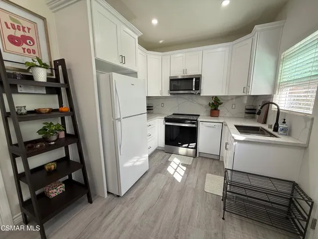 a kitchen with a refrigerator stove and white cabinets