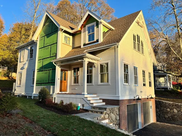 a view of a brick house with a yard plants and large trees