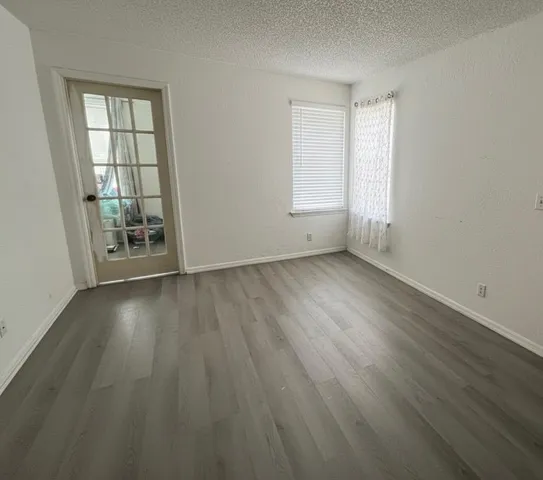 an empty room with wooden floor and windows