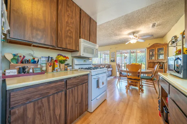 a kitchen with stainless steel appliances granite countertop a refrigerator a sink dishwasher a dining table and chairs with wooden floor