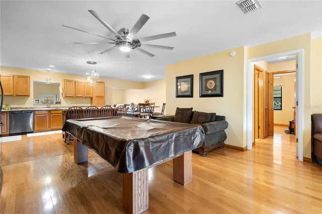 a living room with stainless steel appliances kitchen island granite countertop furniture and a wooden floor