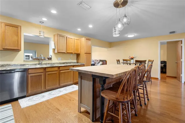 a kitchen with stainless steel appliances kitchen island granite countertop a sink a stove a dining table and chairs