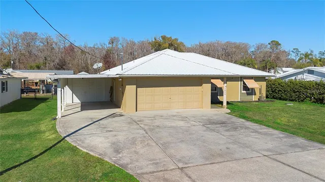 a view of a white house next to a yard with big trees