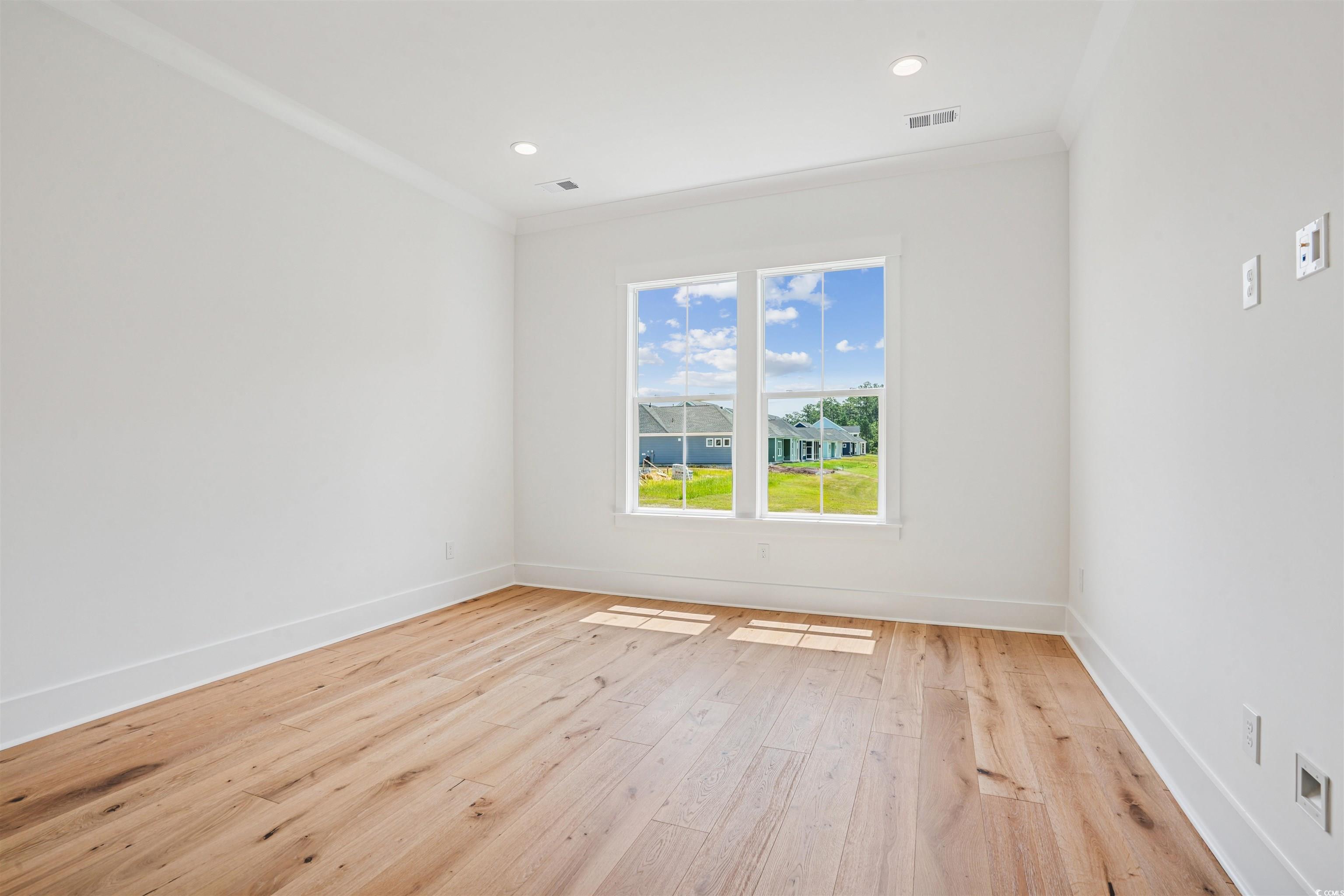 6709 Genesis Drive Murrells Inlet, SC 29576 - Photo 8 of 14 Empty room with crown molding, light wood-type flo