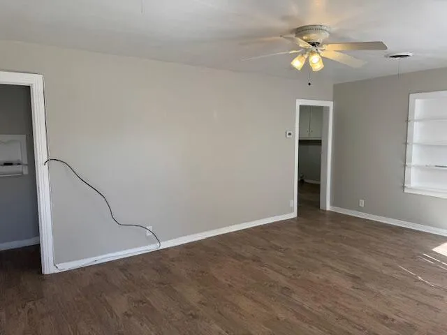 an empty room with wooden floor fan and windows