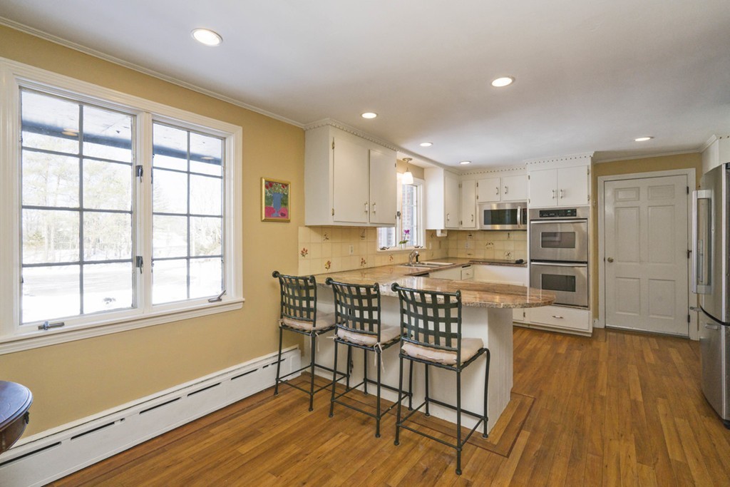 62 Rust Way Cohasset, MA 02025 - Photo 3 of 17 a kitchen with stainless steel appliances granite countertop a stove top oven a refrigerator a dining table and chairs with wooden floor