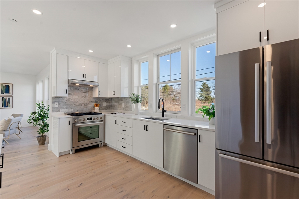 656 Mystic Avenue, Unit B Somerville, MA 02145 - Photo 14 of 40 a kitchen with white cabinets stainless steel appliances and a potted plant