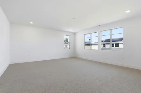 an empty room with windows and view of kitchen