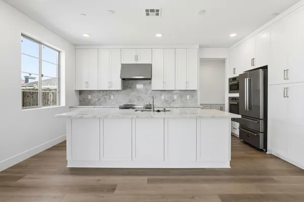 a kitchen with stainless steel appliances granite countertop a refrigerator sink and white cabinets