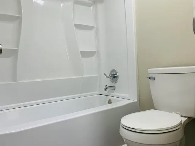 a white toilet sitting next to a bath tub