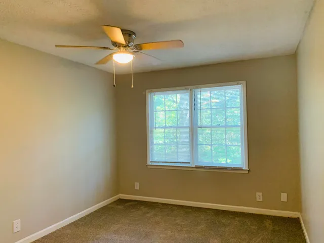 an empty room with a window and a ceiling fan