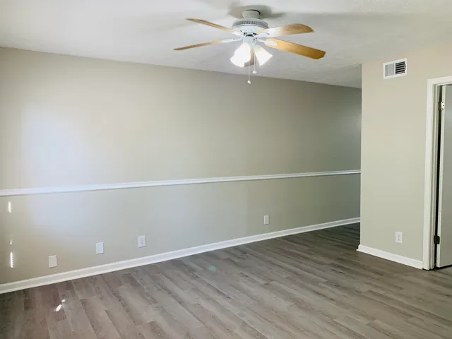 an empty room with wooden floor and fan