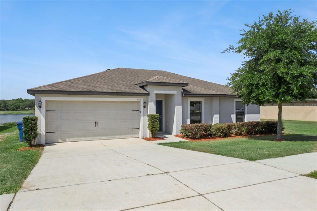 1613 Orne Street Mascotte, FL 34753 - Photo 3 of 31 a front view of a house with a yard and garage