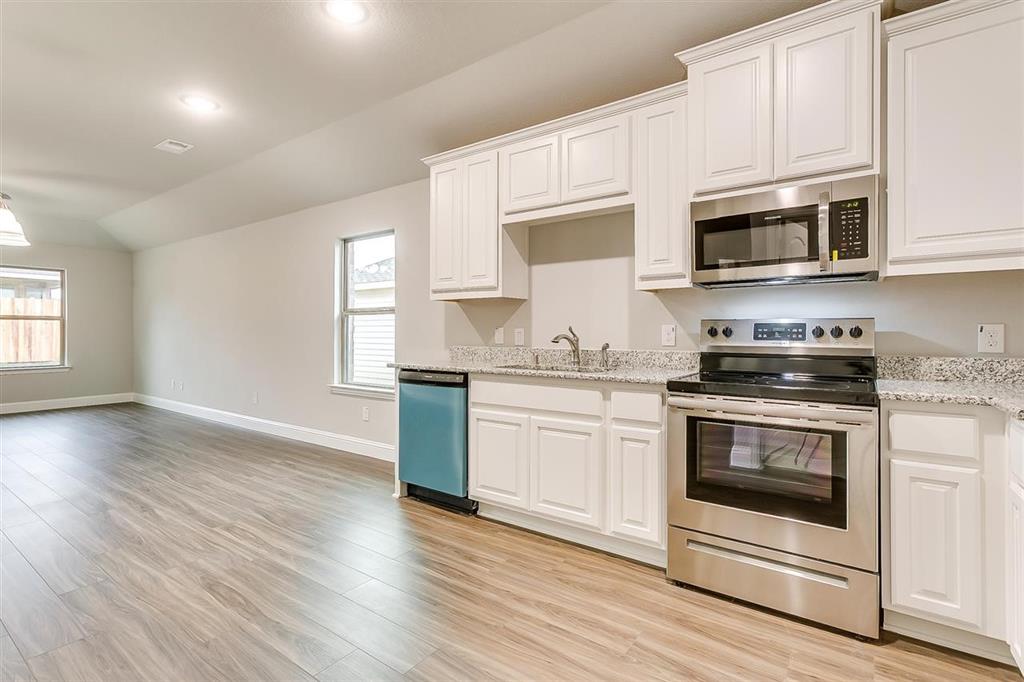 a kitchen with stainless steel appliances granite countertop a stove a microwave and white cabinets
