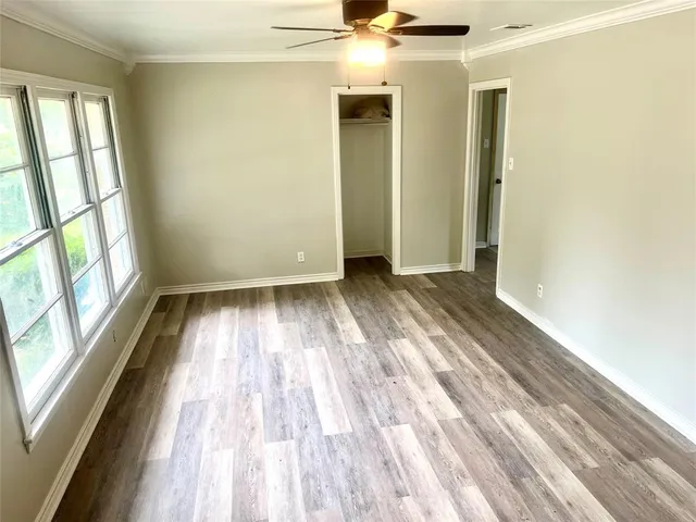 a view of empty room with wooden floor and fan