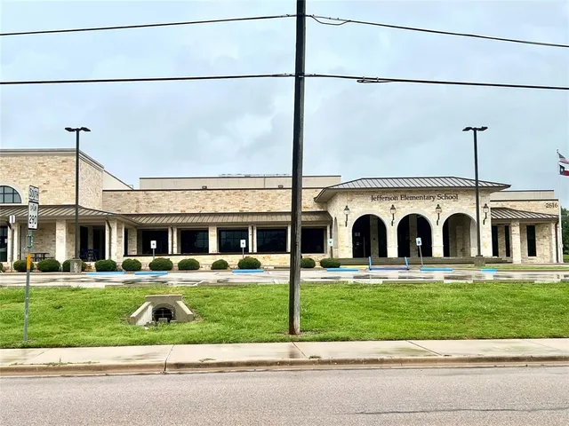 a view of a white house with a big yard and potted plants