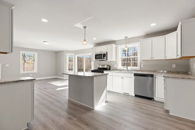 a kitchen with granite countertop white cabinets and wooden floor