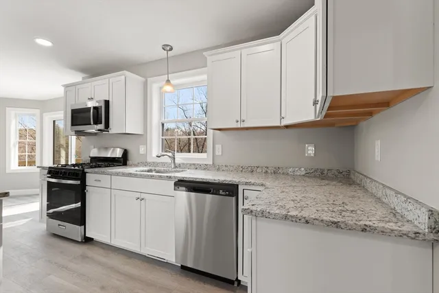 a kitchen with stainless steel appliances granite countertop a sink a stove and cabinets