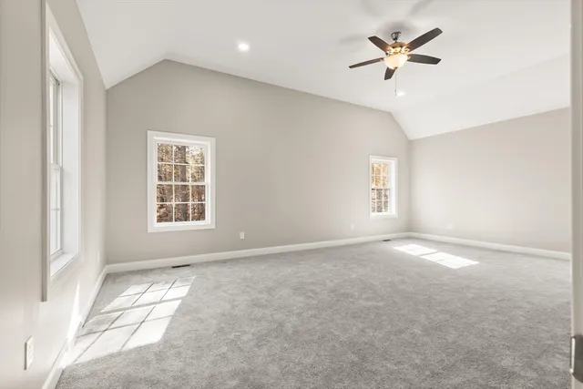 an empty room with windows and ceiling fan