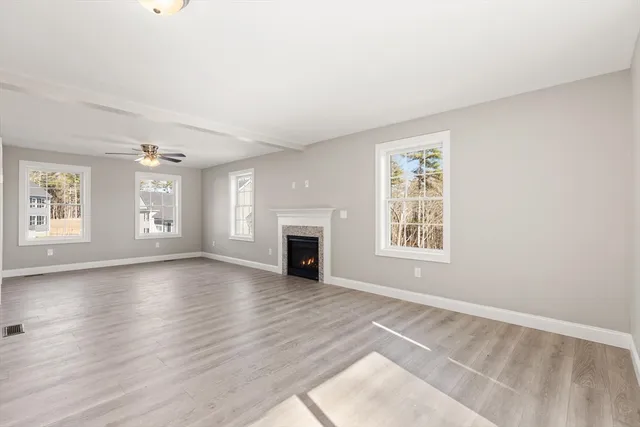 an empty room with wooden floor fireplace and windows