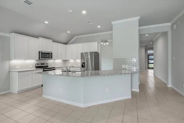 a kitchen with stainless steel appliances granite countertop a stove a sink and a microwave
