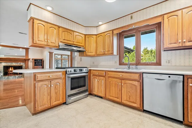 a kitchen with stainless steel appliances granite countertop a stove a sink dishwasher a refrigerator and cabinets with wooden floor