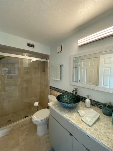 a bathroom with a granite countertop sink toilet a mirror and shower