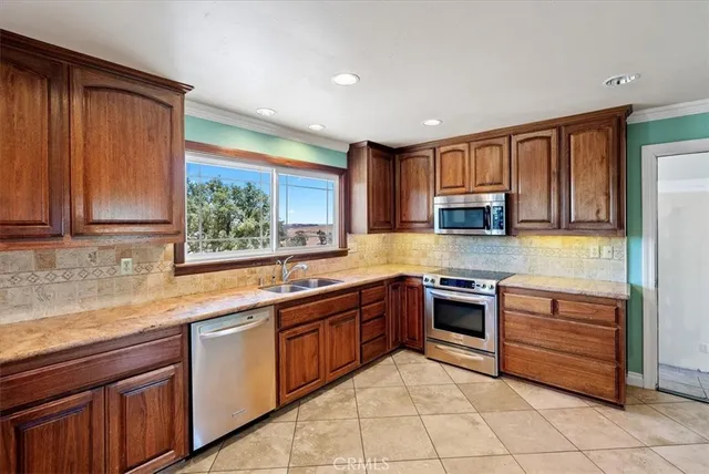 a kitchen with stainless steel appliances granite countertop wooden cabinets a sink and dishwasher a stove top oven with wooden floor