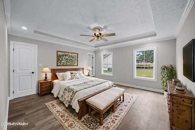 a living room with a bed furniture flat screen tv and a large window