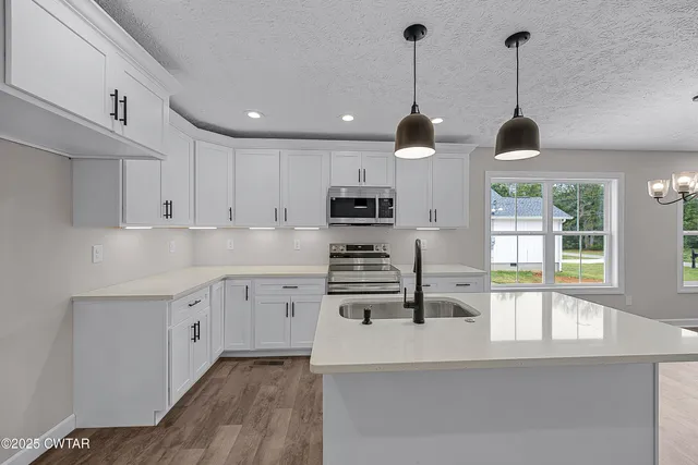 a kitchen with stainless steel appliances granite countertop a stove a sink and a wooden floors