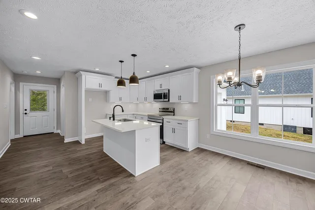 a large kitchen with kitchen island a large counter space a sink appliances and cabinets