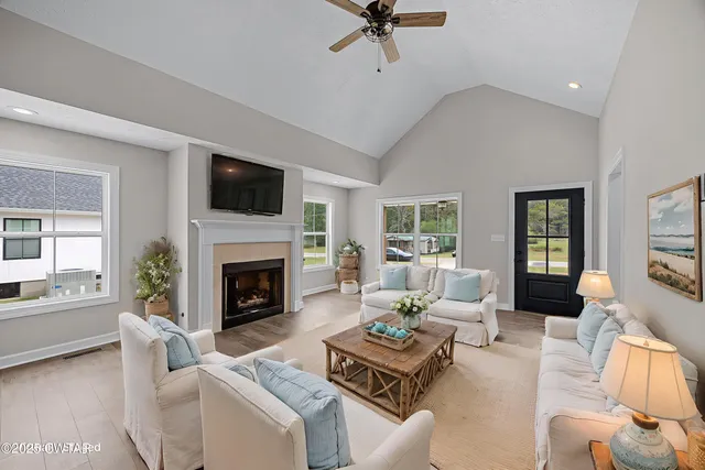 a living room with furniture a fireplace a flat screen tv and a large window