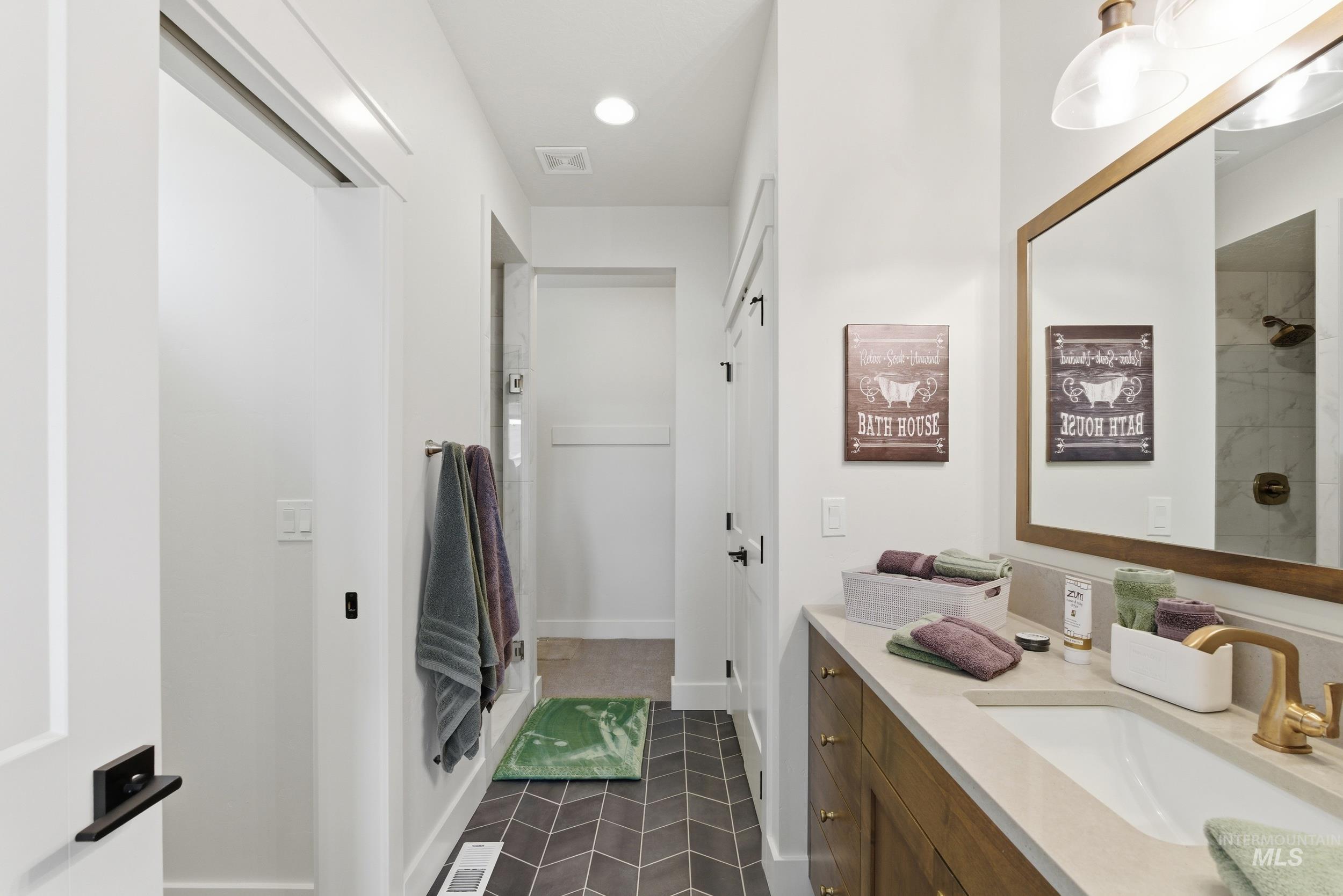6347 South Utmost Lane Meridian, ID 83642 - Photo 17 of 37 Bathroom guest suite featuring a single vanity with wood-finish cabinetry, light-toned countertop, and gold-finish fixtures